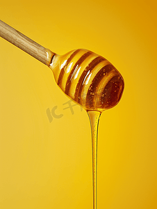黄色背景上的木制蜂蜜勺子里滴着金色的蜂蜜