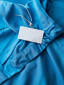 描述如实摄影照片_蓝色连衣裙上的空白白色洗衣护理服装标签
