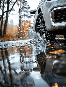 灰色汽车摄影照片_灰色汽车穿越水坑日光下溅水特写采用散焦技术