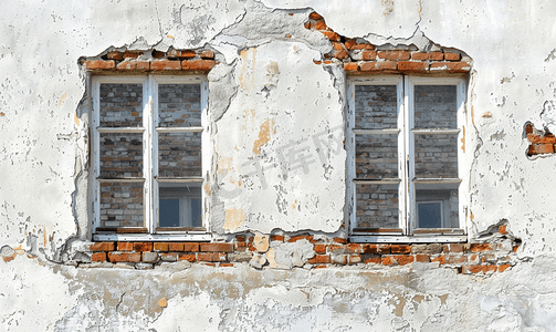 厚砖中世纪墙上的两扇窗户在磨损的白色灰泥层下