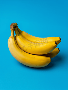 水果的创意摄影照片_新鲜成熟的水果香蕉黄色孤立在蓝色背景上