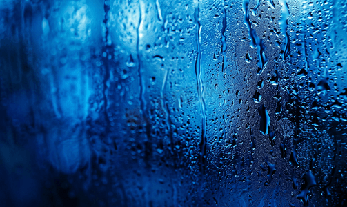 夜湿窗玻璃的抽象背景带有蓝色调伽马污迹