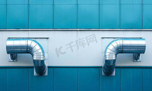 白色和蓝色工业建筑外墙上的镀铬通风管