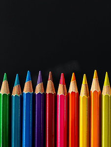 创意背景图形摄影照片_黑色背景上的彩色彩虹铅笔行渐变