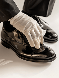 刷鞋摄影照片_戴白手套擦黑鞋的擦鞋工