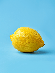 蓝色背景简约摄影照片_蓝色背景中突显的新鲜美味柠檬创意简约食品概念