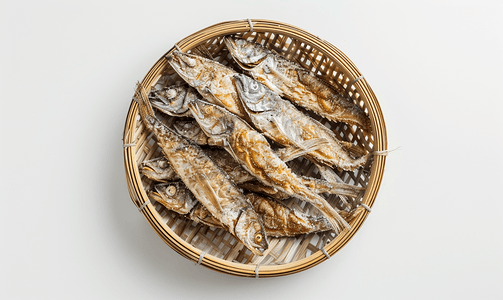 咸摄影照片_白色背景中隔离的竹柳条上排列的咸干鱼的顶部视图