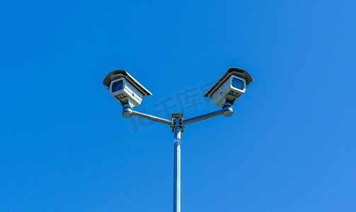 蓝天背景城市摄影照片_蓝天背景中路灯杆上的两个旧闭路电视安全监控摄像头