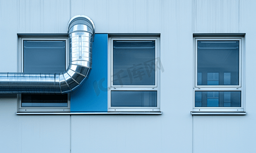 白色和蓝色工业建筑外墙上的镀铬通风管