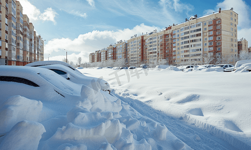 阳光明媚的日子里住宅楼附近停车场的汽车被埋在雪下