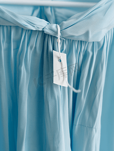 热销爆款标签摄影照片_蓝色连衣裙上的洗衣护理服装标签