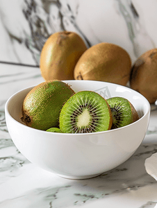 水果厨房背景摄影照片_大理石厨房桌子上的白色碗里放着猕猴桃新鲜多汁的热带水果
