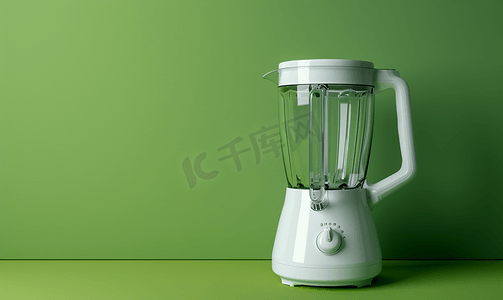 绿色背景上带空玻璃杯的白色搅拌机