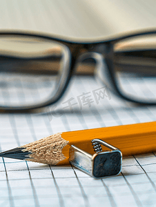 在纸上用铅笔刀特写一支铅笔在背景上用橡皮擦尺子眼镜
