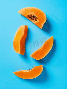 明亮色彩摄影照片_蓝色背景中的橙色木瓜片