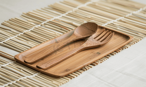 木制菜单摄影照片_竹制底板上的天然木质盘子、勺子和叉子