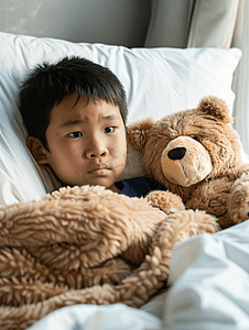 流感病人摄影照片_亚洲男孩患流感棕熊躺在病床上治