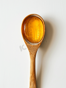 吃蜂蜜摄影照片_木勺中的蜂蜜具有白色背景中突显的甜味