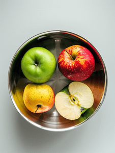 金属碗配有绿黄红苹果和一个被咬的苹果特写顶视图