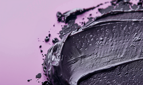 涂抹纹理摄影照片_紫色背景黑粘土面膜擦洗化妆品泥涂抹