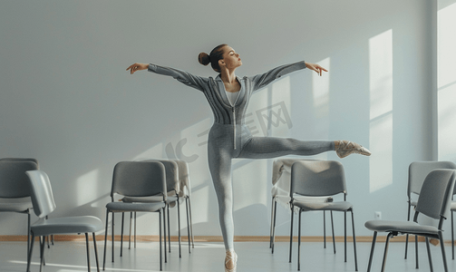 身穿灰色条纹套装的芭蕾舞女演员站在椅子之间脚踩足尖鞋做着屈膝姿势