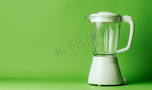 绿色背景上带空玻璃杯的白色搅拌机