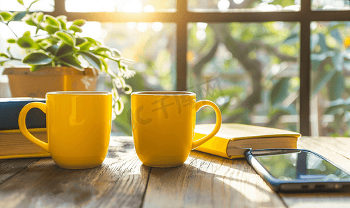 饮料组合摄影照片_屋内木桌上的黄色咖啡杯电话和书籍