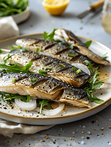 桌上盘子里放着切好的咸鲱鱼、洋葱和芝麻菜简单的小吃