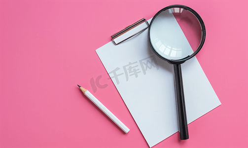 放大镜铅笔和粉红色弹簧上的空白白色记事本