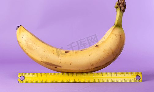 使用紫色背景上的黄色尺子测量去皮香蕉的长度