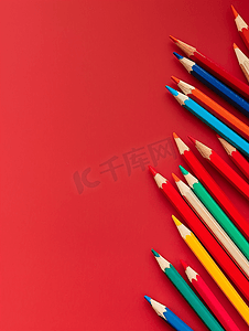 彩色木铅笔散落在红色背景教育概念上