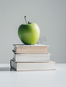 桌子书籍摄影照片_一个绿色的苹果盘旋在白色背景上孤立的书籍上