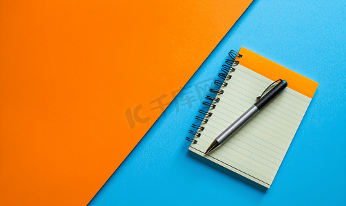 有笔的笔记本和蓝色和橙色背景上的彩色笔记