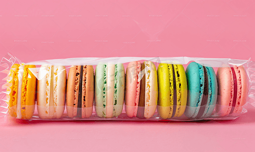 反塑料包装摄影照片_粉色背景包装中的彩色法式马卡龙饼干