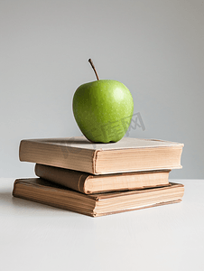一个绿色的苹果盘旋在白色背景上孤立的书籍上