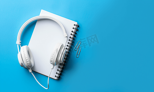 弹簧夹上的有线白色耳机记事本和蓝色按钮