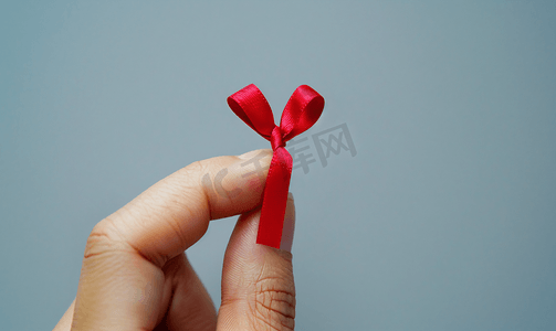 廉洁提醒摄影照片_提醒男性手指的特写用红丝带绑住并孤立在白色