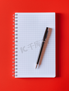 打开弹簧上的笔记本和红色背景副本上的黑色圆珠笔