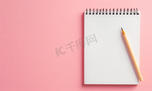 粉色学校摄影照片_粉色背景上有白页和木铅笔的空白螺旋记事本