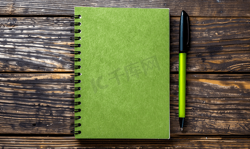 棕色木桌顶视图上带有毡尖笔的绿色记事本