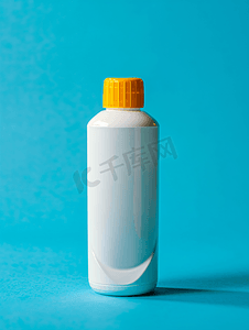 国画蓝色荷花摄影照片_蓝色背景中带黄色帽子的白色塑料瓶和洗发水凝胶