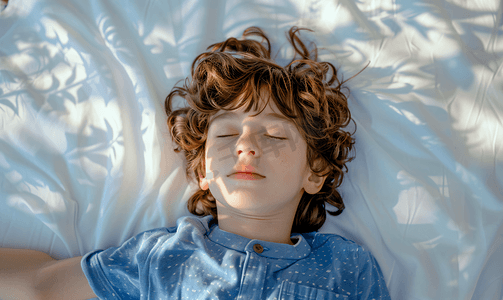 一个孩子穿着蓝色衬衫躺在白床单上