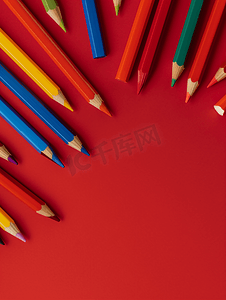 彩色木铅笔散落在红色背景教育概念上
