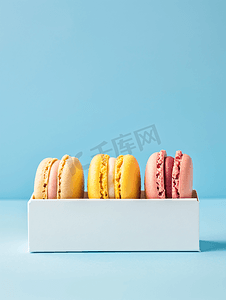 黄色的蛋糕摄影照片_蓝色背景白盒中的多彩多姿的法国通心粉饼干