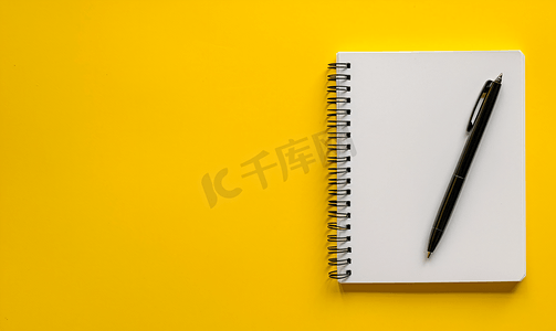 黄色背景上的笔记本和笔带复制空间的顶视图