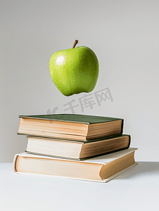 一个绿色的苹果盘旋在白色背景上孤立的书籍上