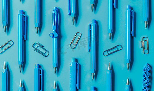 铅笔圆规摄影照片_钢笔、铅笔、圆规、回形针排成线全部为蓝色背景为