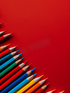 寒假招生艺术字摄影照片_彩色木铅笔散落在红色背景教育概念上