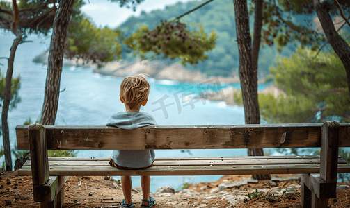 一个孤独的孩子在森林里的长椅上休息欣赏海景