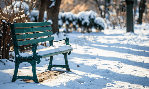 冬季积雪覆盖的城市花园中的绿色长椅